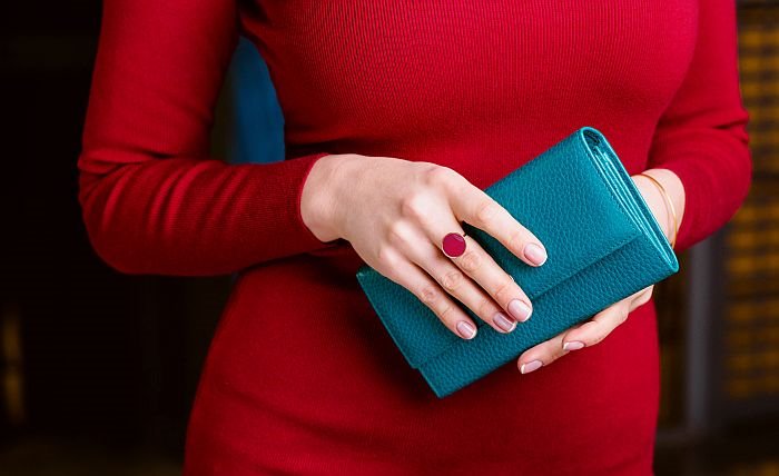 Žena u crvenom drži plavi novčanik