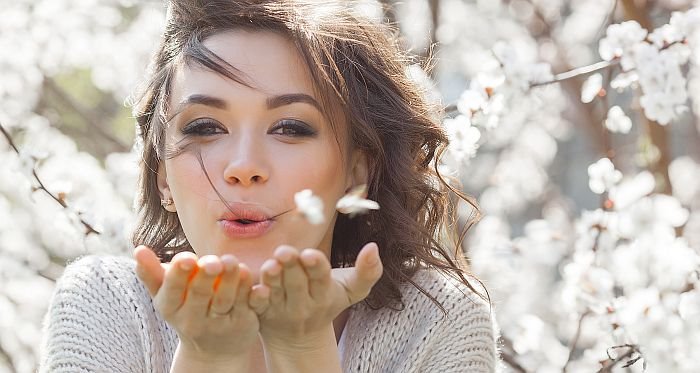 Devojka duva prolećno cveće s dlana