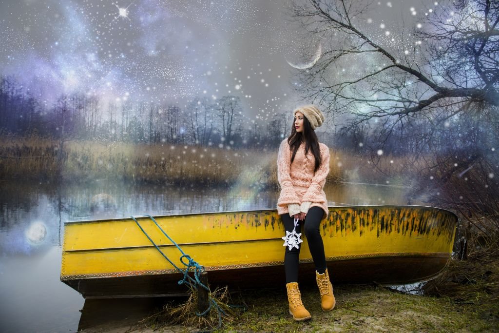 Devojka stoji kraj čamca na zaleđenom jezeru