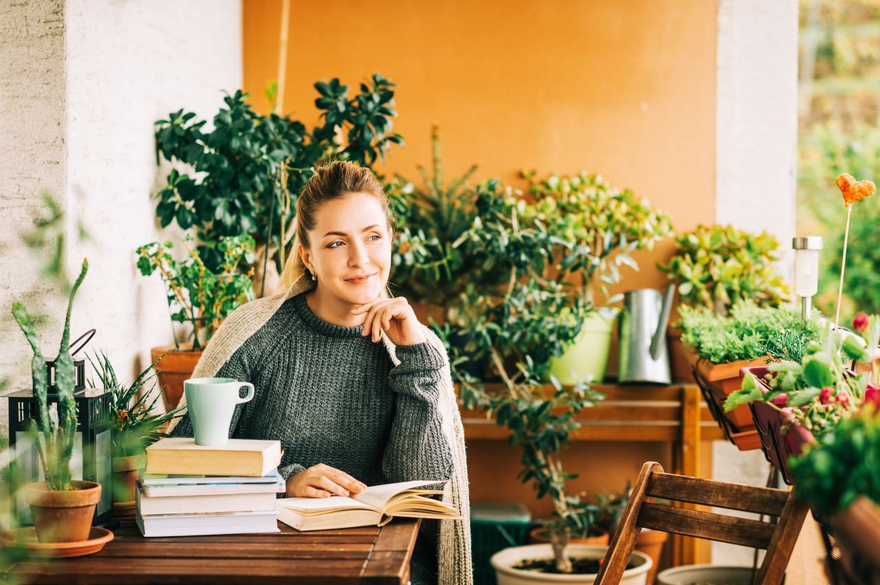 Žena čita u sobi punoj biljaka