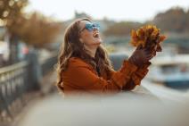 Devojka skuplja lišće i smeje se