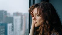 Žena tužno gleda kroz prozor