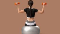 Žena sedi na pilates lopti i vežba mišiće leđa
