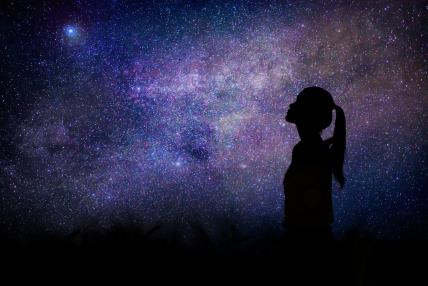 Devojka gleda u zvezdano nebo