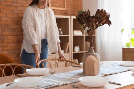 Žena namešta sto na kom je buket suvog cveća