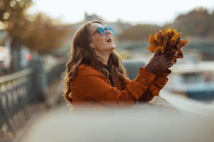 Devojka skuplja lišće i smeje se