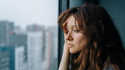 Žena tužno gleda kroz prozor