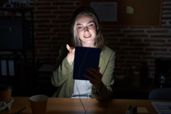 Žena u mraku odgovara na mejl na tabletu