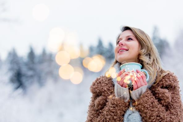 Devojka pije topli napitak na snegu i srćna je