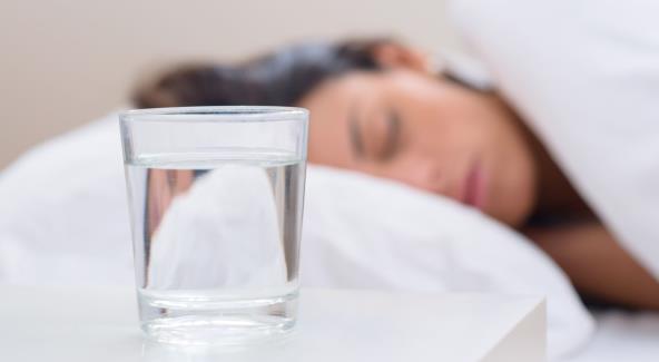 Žena spava i čaša vode na noćnom ormariću