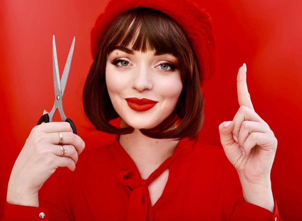 Žena u crvenom drži makaze